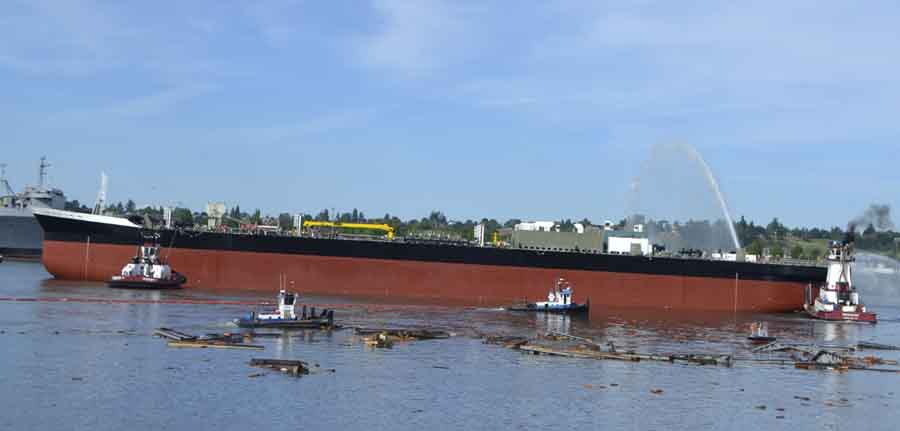 After its descent, the Kirby 185-01 floats toward the middle of the River, where tugboats guide it and a smaller boat wraps a boom to gather up the wood that fell into the River.