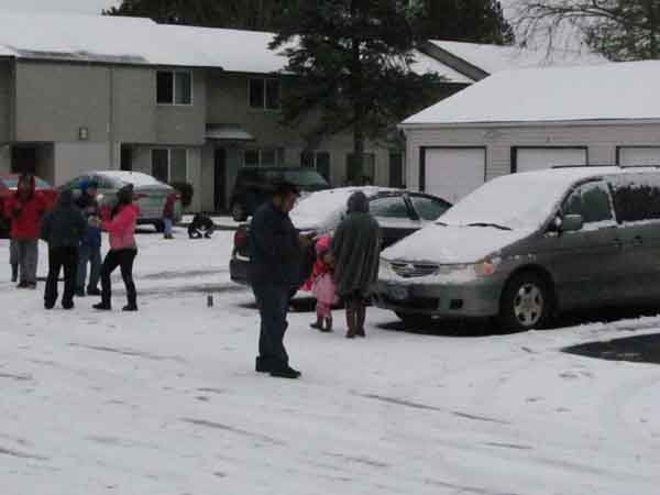 Apartment residents bring their children outside to revel in less than an inch of snow on the ground.